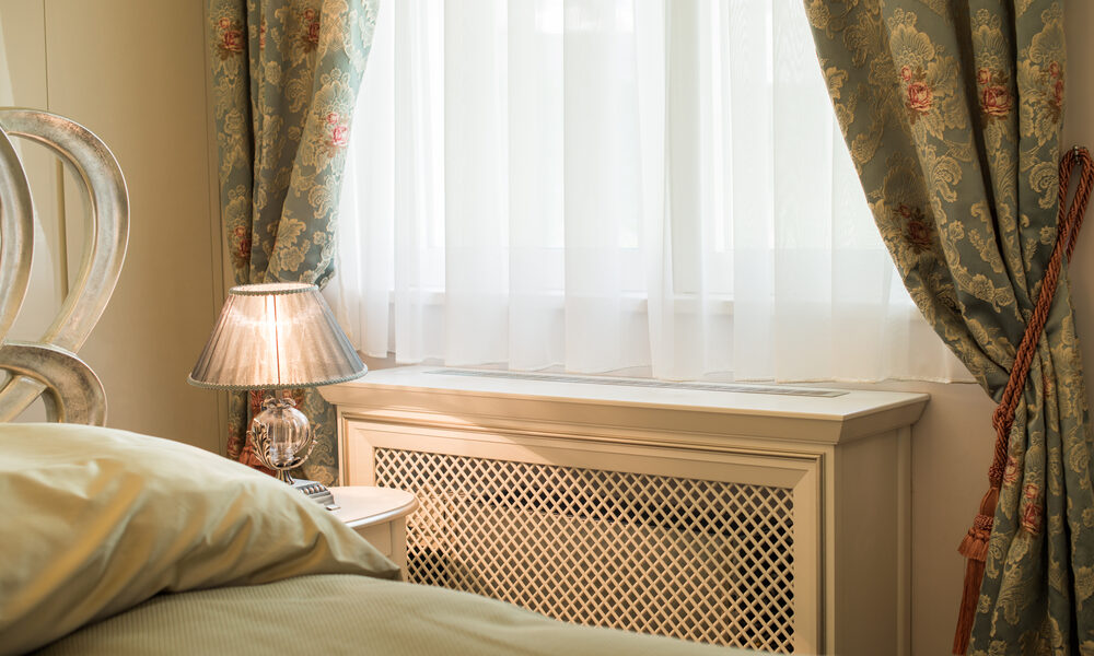 A radiator with a wooden cover in a bedroom