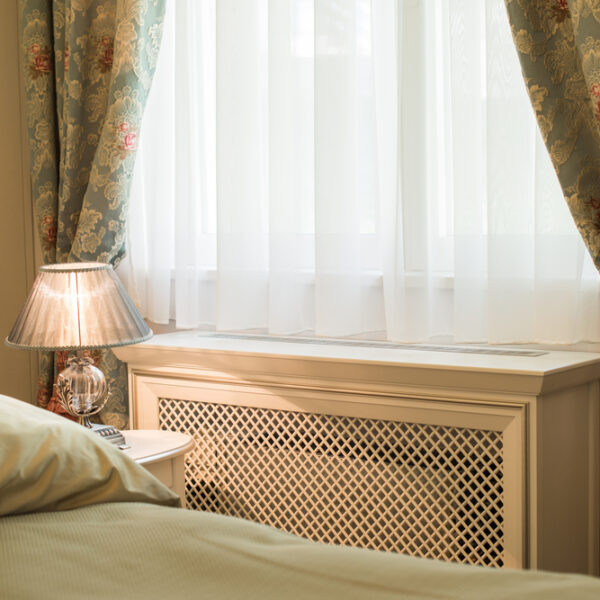 A radiator with a wooden cover in a bedroom